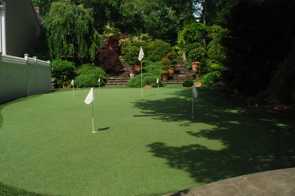 Austin Synthetic grass golf green with flags in a landscaped backyard